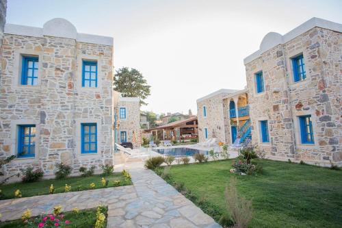 a large stone building with blue windows and a yard at LA Petra Boutique HOTEL in Datca