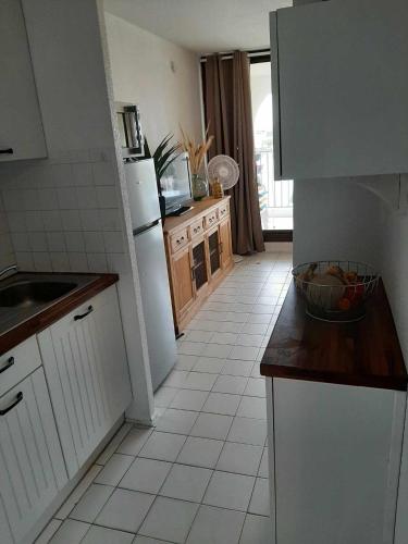 une cuisine avec un sol en carrelage blanc et des appareils électroménagers blancs dans l'établissement Entre Mer et Corbières, au Barcarès