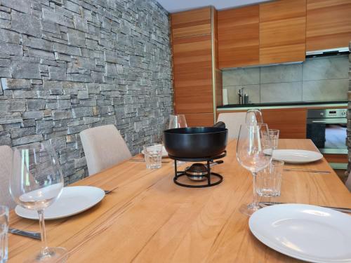 a dining room table with wine glasses and a stone wall at A Quiet Place in Siviez