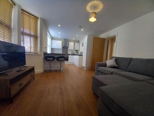 a living room with a couch and a tv and a kitchen at Comfortable and spacious 2 bedrooms Free parking in Nottingham