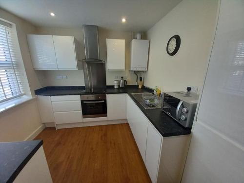 a kitchen with white cabinets and a clock on the wall at Comfortable and spacious 2 bedrooms Free parking in Nottingham