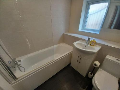 a bathroom with a tub and a sink and a toilet at Comfortable and spacious 2 bedrooms Free parking in Nottingham