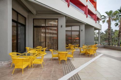 a group of yellow tables and chairs on a patio at Megasaray Resort Side in Side