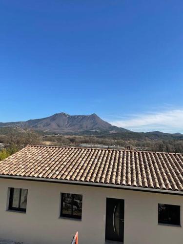 une maison blanche avec un toit avec des montagnes en arrière-plan dans l'établissement Appartement neuf dans villa, à Aiglun