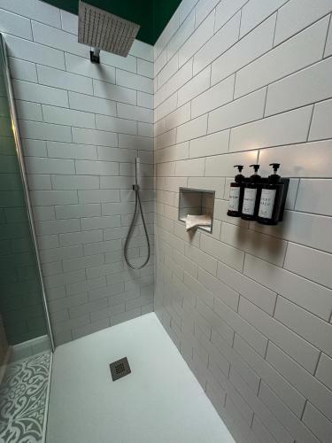 a white tiled bathroom with a shower with a hose at The Hideaway - Luxury Country Retreat in The Trench