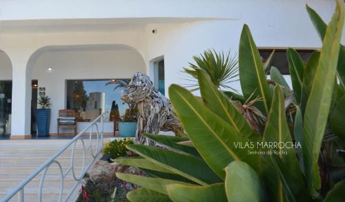 a statue of a bird standing next to some plants at Vilas Marrocha in Porches