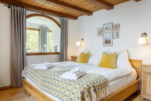 a bedroom with a bed with yellow and white pillows at Chesa-strimer - Veranda in La Punt-Chamues-ch