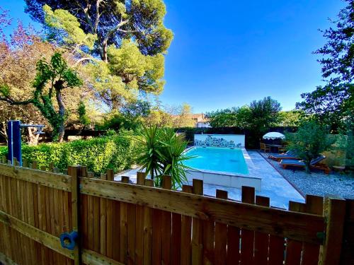 une cour avec une clôture en bois et une piscine dans l'établissement Gîtes La Maison près de la fontaine et La Cabane du Pêcheur, à Talairan