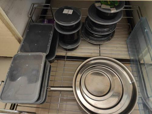 a stack of plates and pans sitting on a shelf at Pet Friendly Studio Apartment in Hadapsar in Pune