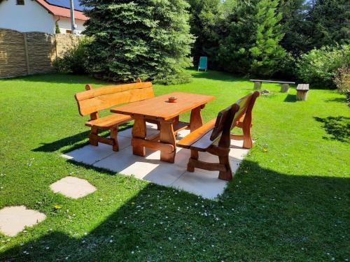 a wooden picnic table and two benches in a yard at V přírodě na okraji Frenštátu pod Radhoštěm in Frenštát pod Radhoštěm