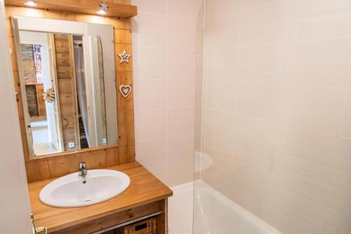 une salle de bain avec un lavabo, un miroir et une baignoire dans l'établissement Résidence Le Balcon Des Airelles - Le Lodge d'Orres situé au coeur de 1800 MAE-4211, aux Orres