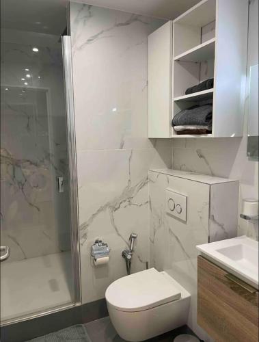 une salle de bain blanche avec toilettes et douche dans l'établissement Paris Esplanade 701, à Courbevoie