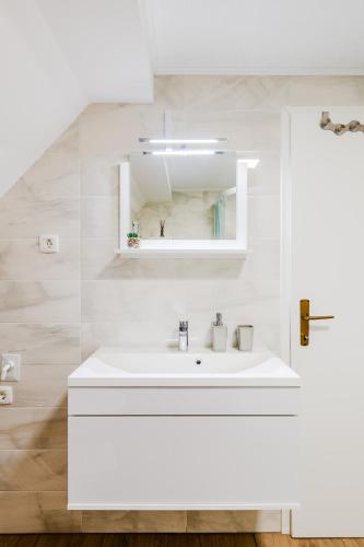 a white bathroom with a sink and a mirror at Apartmaji Mouse in Bovec