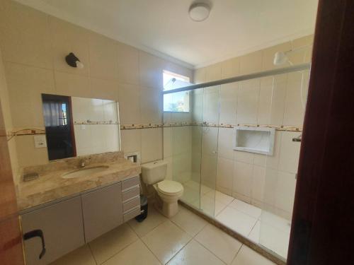 ein Badezimmer mit Toilette, Waschbecken und Spiegel in der Unterkunft Casa Balneário in São Pedro da Aldeia