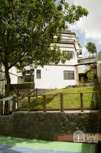 a white building with a tree and a fence at Hotel Bellavista Quito in Quito