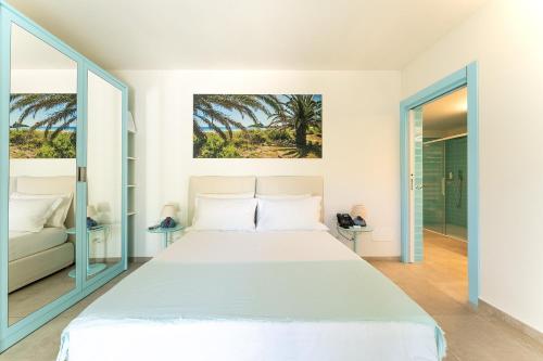 a white bedroom with a large bed and a window at Oasi Blu Sardinia in Santa Margherita di Pula