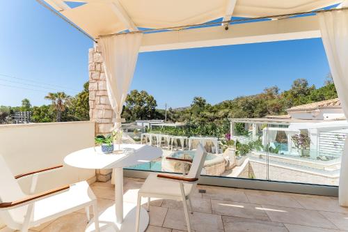 a balcony with a table and chairs and a large window at Oasi Blu Sardinia in Santa Margherita di Pula