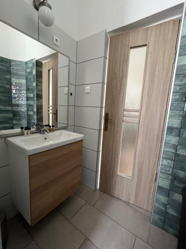 a bathroom with a sink and a mirror and a door at Délceg Réce Minihotel in Balatonkenese