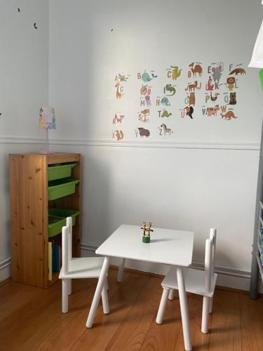 une table et des chaises blanches dans une chambre avec un mur dans l'établissement Grand logement 5 min de Paris, à Aubervilliers
