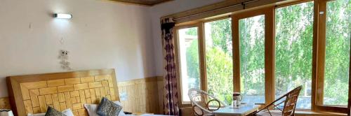 a living room with a table and chairs and windows at Hotel Namgyal Villa in Nubra