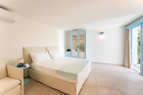 a white bedroom with a bed and a couch at Oasi Blu Sardinia in Santa Margherita di Pula