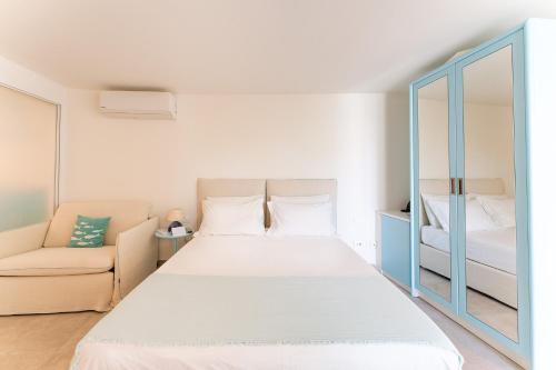 a bedroom with a bed and a couch and a mirror at Oasi Blu Sardinia in Santa Margherita di Pula