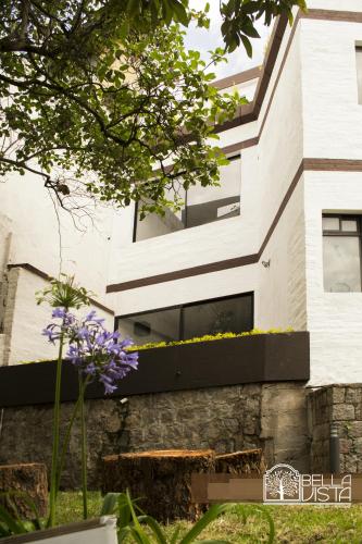 a white house with black windows and purple flowers at Hotel Bellavista Quito in Quito