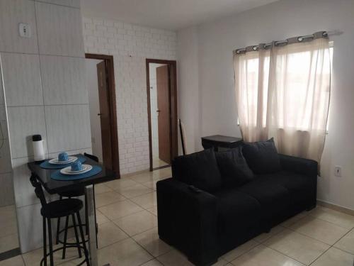 a living room with a black couch and a table at Apartamento Encantador 201 in Vitória da Conquista