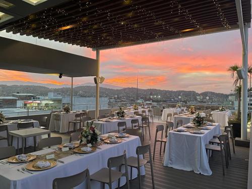 a restaurant with white tables and chairs with a sunset at Hotel CasaBlanca Cucuta in Cúcuta