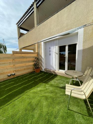 a patio with a table and a chair on the grass at Studio à l'Ecurie in Narbonne