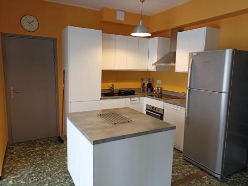 une cuisine avec un réfrigérateur en acier inoxydable et des armoires blanches dans l'établissement Gîte 8 pers -climatisé avec jardin- proche plage, à Elne