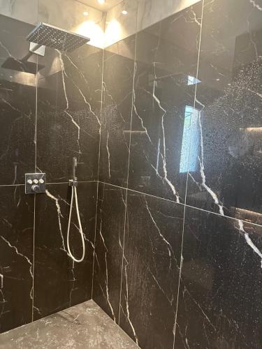 La salle de bains est pourvue de murs en marbre noir et d'une douche. dans l'établissement Villa avec piscine, à Rochefort-du-Gard