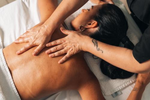 a woman getting a back massage from a therapist at Oasi Blu Sardinia in Santa Margherita di Pula