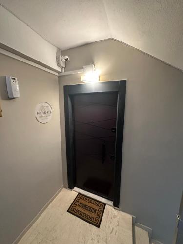 a hallway with a black door with a welcome mat at The Heidi's Central House in Kos Town