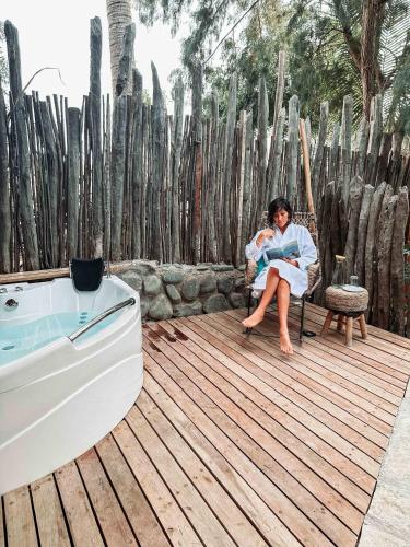 a woman sitting in a chair next to a bath tub at AguaMar Vichayito in Los Órganos
