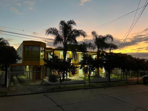 a building with palm trees in front of a sunset at Cybeles Family Apart in Villa Carlos Paz