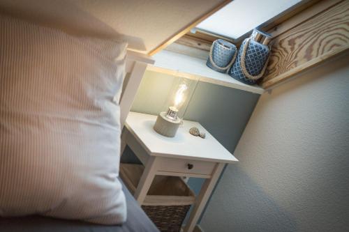 a bed with a table with a lamp on a side table at Ferienwohnungen Christina Erisgen in Olderup
