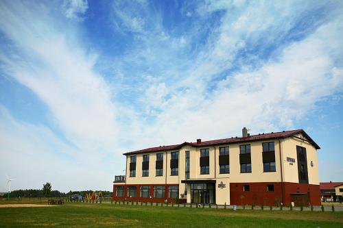 a building in a field with a blue sky at Hippika in Połchowo