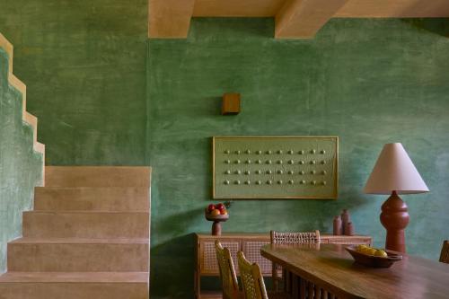a dining room with a table and a green wall at Punta Nayaá - Adults Only in Puerto Escondido