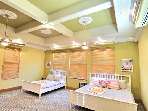 two beds in a room with yellow walls and windows at Stars Manor-Disney-Universal-Pool-22people in Kissimmee