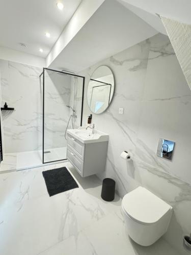 a white bathroom with a toilet and a sink at Aura Castle in Picquigny