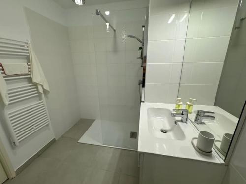 une salle de bain blanche avec un lavabo et une douche dans l'établissement Domaine Eden Golfe 215, à Cogolin