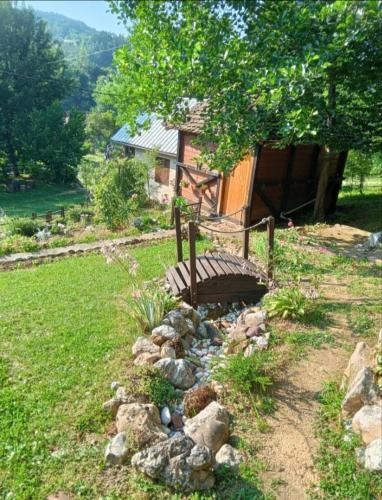 a wooden bench sitting in a yard with rocks at Vikendica Vučetić Loznica in Budimlija