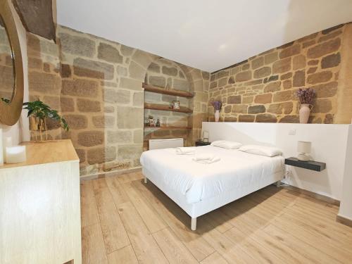 a bedroom with a white bed and a stone wall at Le One, cosy et authentique in Brive-la-Gaillarde