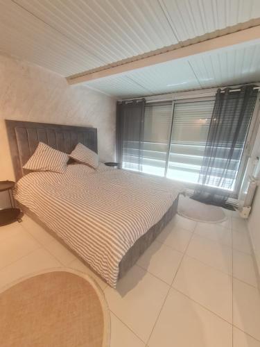 une chambre avec un lit et une grande fenêtre dans l'établissement Apparemment lumineux, à Pierrefitte-sur-Seine