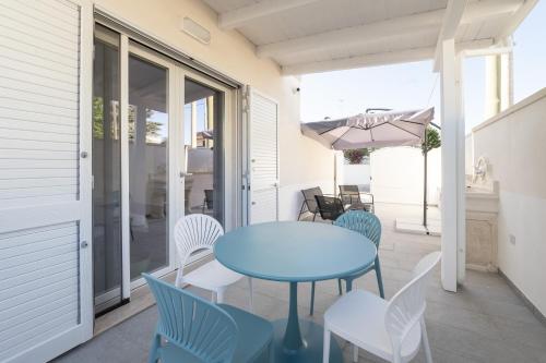 una mesa azul y sillas en un porche con sombrilla en Briamar Residence, en Torre dell'Orso