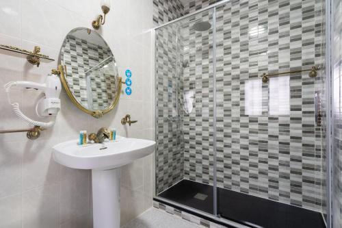 a bathroom with a sink and a shower with a mirror at Hotel La Quinta de Santillán in Chinchón