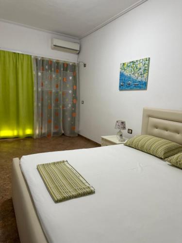 1 dormitorio con cama blanca y cortina verde en Megrooms, en Sarandë