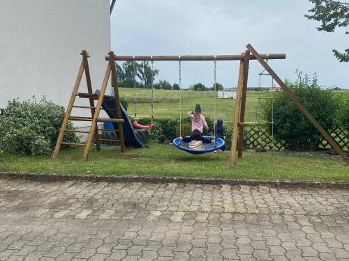 a girl sitting on a swing in a playground at Apartment Wohner in Petersaurach