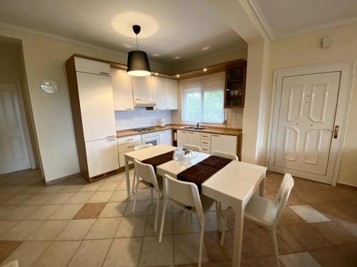 een keuken met een witte tafel en witte stoelen bij Cozy Maisonette Rebecca in Hanioti